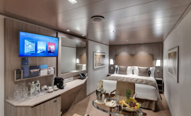 Luxurious MSC Yacht Club Interior Suite on MSC Seaview, featuring a plush queen-size bed, a spacious sitting area with a sofa, ambient lighting, and exclusive Yacht Club amenities in a refined, windowless setting